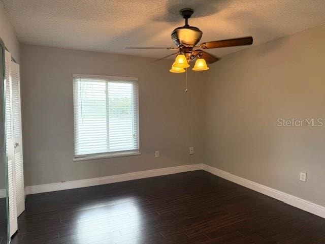 empty room featuring dark hardwood / wood-style floors, ceiling fan, and a textured ceiling