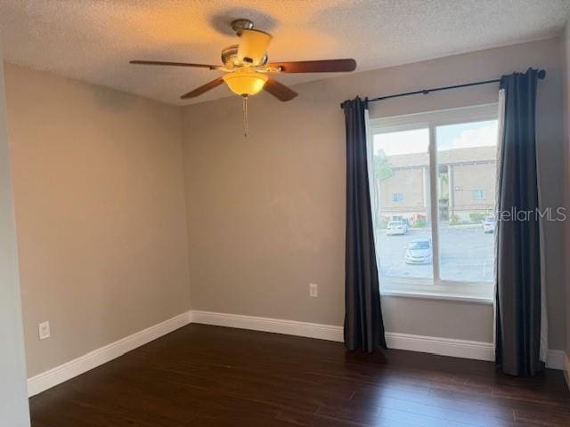 empty room with ceiling fan, dark hardwood / wood-style flooring, and a textured ceiling