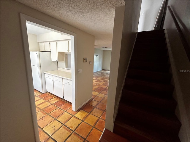 kitchen with white cabinets, a textured ceiling, and white fridge