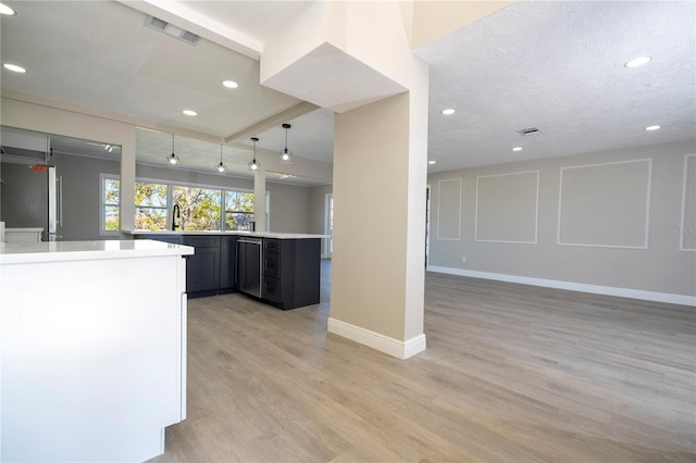 kitchen with decorative light fixtures, sink, stainless steel fridge, kitchen peninsula, and light hardwood / wood-style flooring