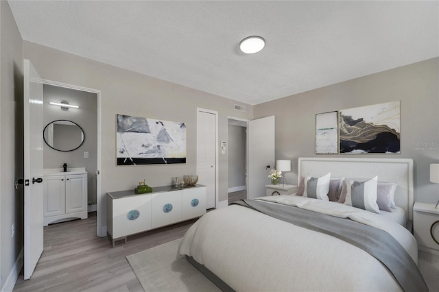 bedroom featuring light hardwood / wood-style floors and a textured ceiling