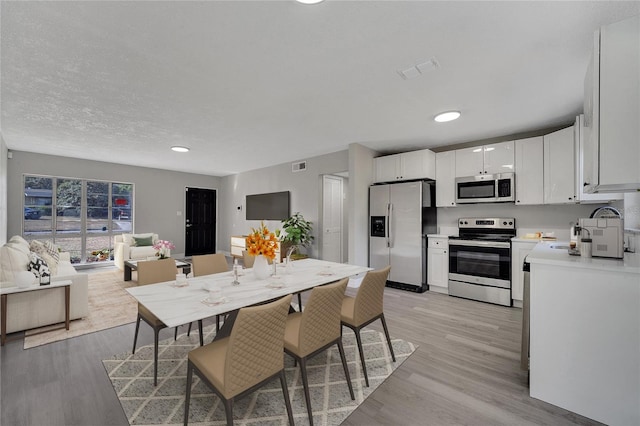 dining area featuring a textured ceiling and light wood-type flooring