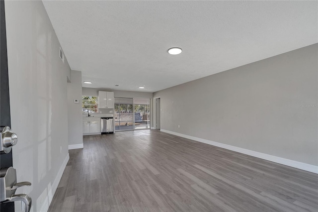 unfurnished living room featuring sink, a textured ceiling, and light wood-type flooring