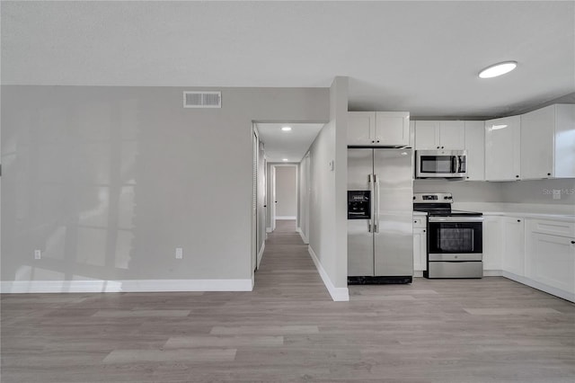 kitchen featuring appliances with stainless steel finishes, light wood-type flooring, and white cabinets