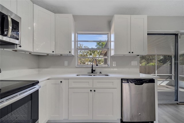 kitchen featuring white cabinetry, sink, stainless steel appliances, and light hardwood / wood-style floors