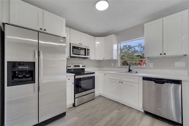 kitchen with white cabinetry, appliances with stainless steel finishes, sink, and light hardwood / wood-style flooring