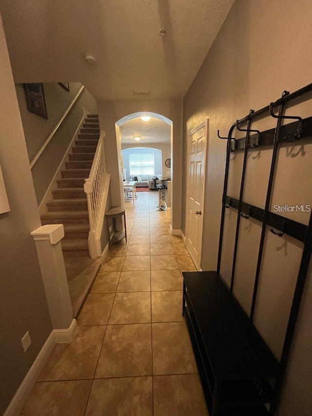 corridor featuring light tile patterned floors and a textured ceiling