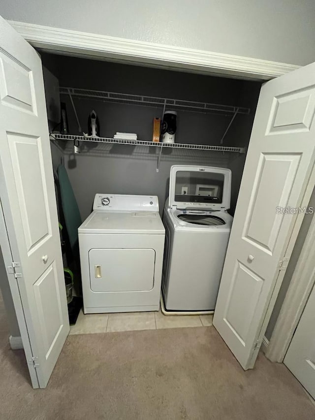 clothes washing area with light tile patterned floors and separate washer and dryer