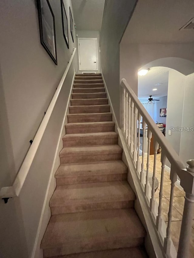 staircase featuring ceiling fan