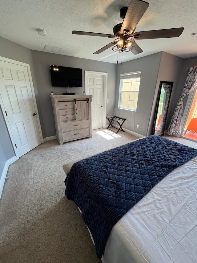 carpeted bedroom featuring ceiling fan and a textured ceiling