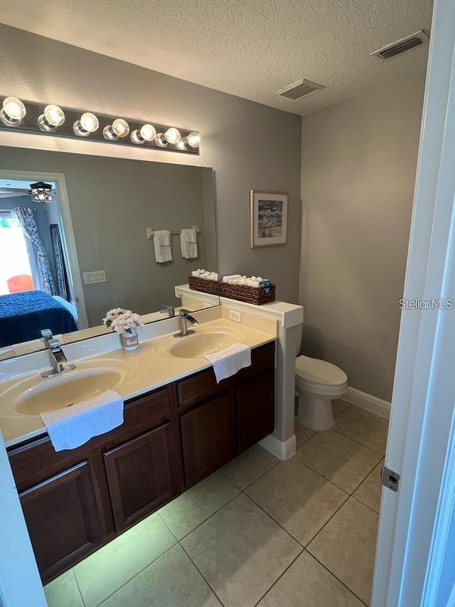 bathroom featuring ceiling fan, tile patterned floors, a textured ceiling, toilet, and vanity