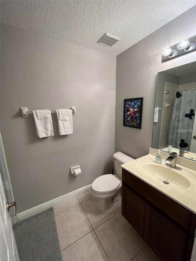 bathroom with tile patterned floors, vanity, a textured ceiling, and toilet