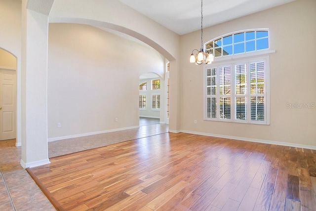 empty room with a chandelier and hardwood / wood-style flooring