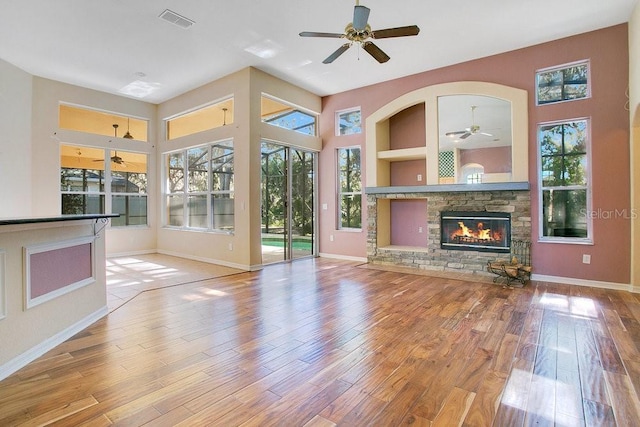 unfurnished living room with a fireplace, wood-type flooring, built in features, and ceiling fan