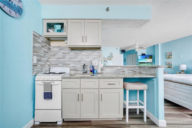 kitchen featuring white cabinets, a kitchen breakfast bar, hardwood / wood-style flooring, ceiling fan, and white electric range oven