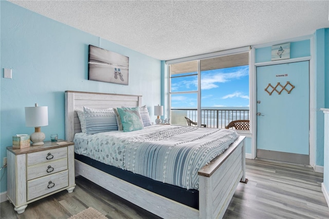 bedroom featuring hardwood / wood-style floors, a water view, and a textured ceiling