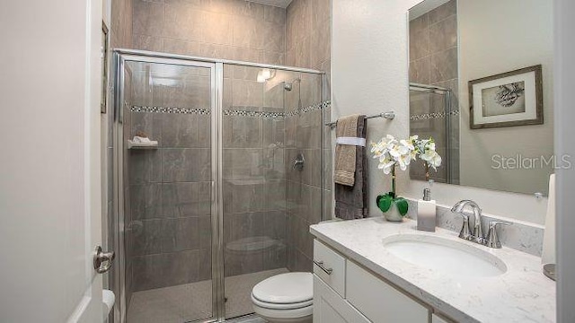 bathroom with vanity, toilet, and a shower with door