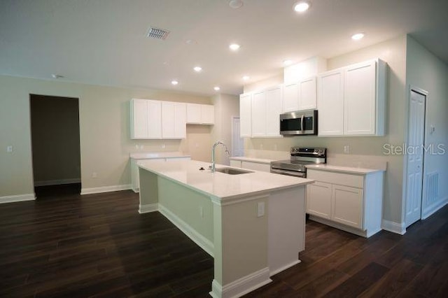 kitchen with dark hardwood / wood-style floors, sink, stainless steel appliances, and a kitchen island with sink