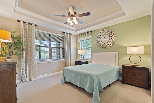 bedroom with a tray ceiling, ornamental molding, a ceiling fan, light carpet, and baseboards