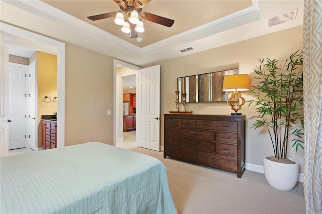 bedroom with a tray ceiling, crown molding, visible vents, light carpet, and baseboards