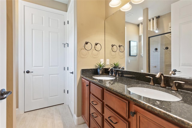 full bathroom with visible vents, a sink, a shower stall, and double vanity