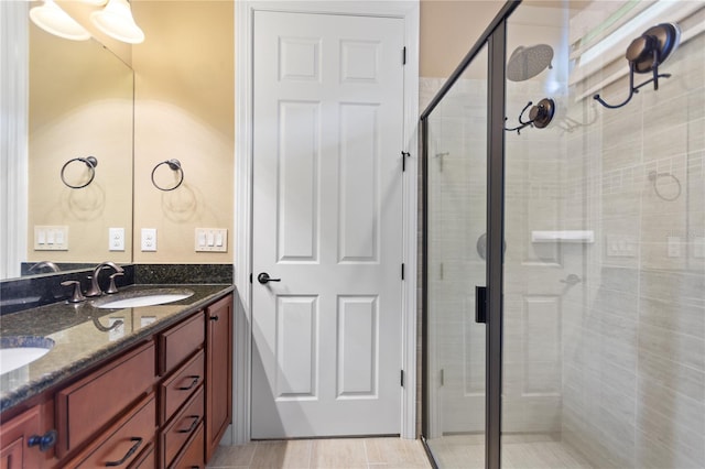 full bath featuring double vanity, a stall shower, and a sink