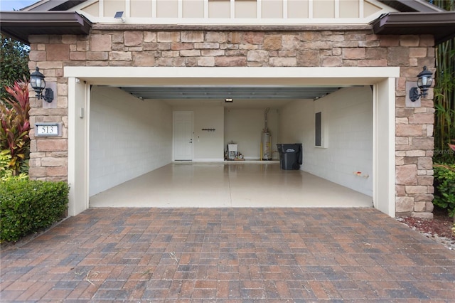 garage with electric panel, gas water heater, and decorative driveway