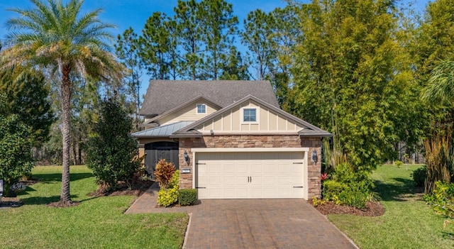 craftsman house with board and batten siding, a front yard, decorative driveway, stone siding, and an attached garage