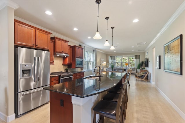 kitchen featuring a sink, stainless steel appliances, under cabinet range hood, crown molding, and open floor plan