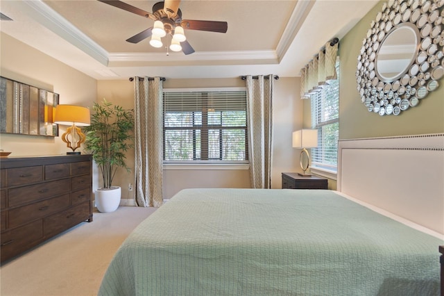 bedroom with carpet, a tray ceiling, multiple windows, and crown molding