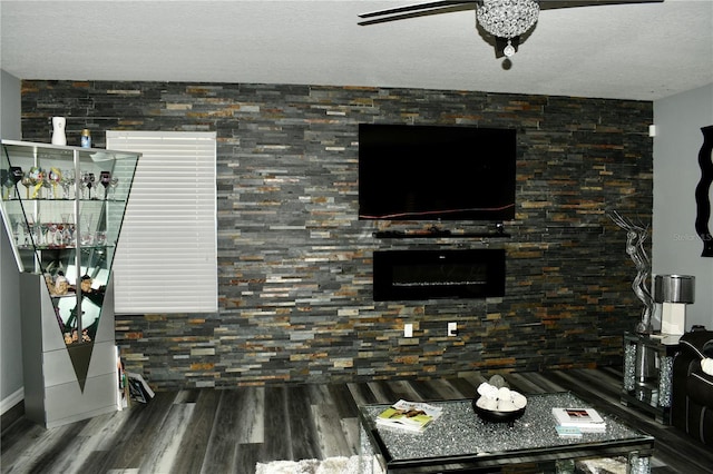 living room with ceiling fan, wood-type flooring, and a textured ceiling