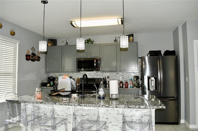 kitchen featuring gray cabinets, dark stone countertops, appliances with stainless steel finishes, tasteful backsplash, and light tile patterned flooring