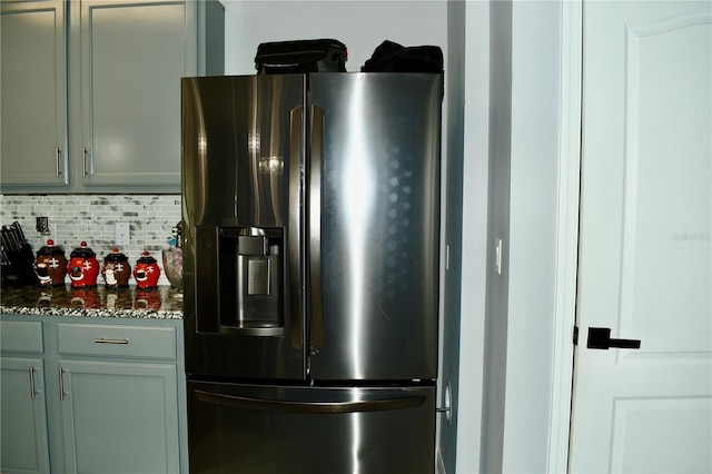 kitchen featuring decorative backsplash, stainless steel fridge with ice dispenser, and dark stone counters