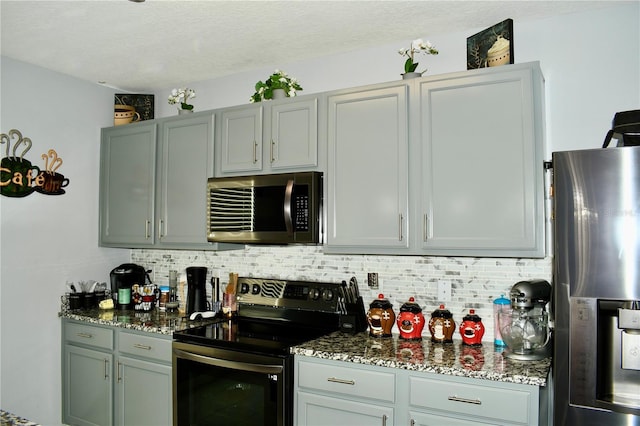 kitchen featuring decorative backsplash, appliances with stainless steel finishes, a textured ceiling, and dark stone countertops