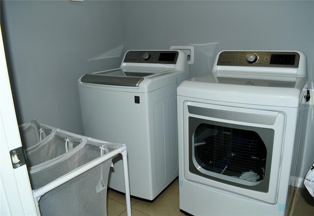 clothes washing area featuring washer and dryer and light tile patterned flooring