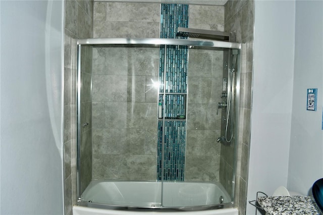 bathroom featuring toilet and combined bath / shower with glass door