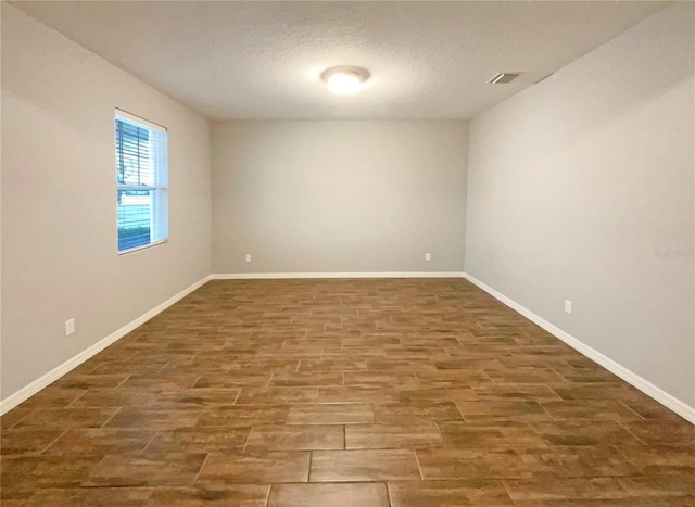 unfurnished room featuring a textured ceiling and dark hardwood / wood-style floors