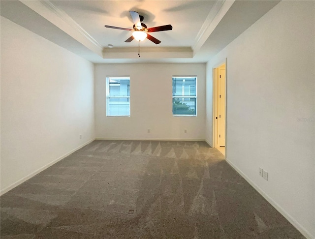 carpeted empty room with a raised ceiling, ceiling fan, and ornamental molding