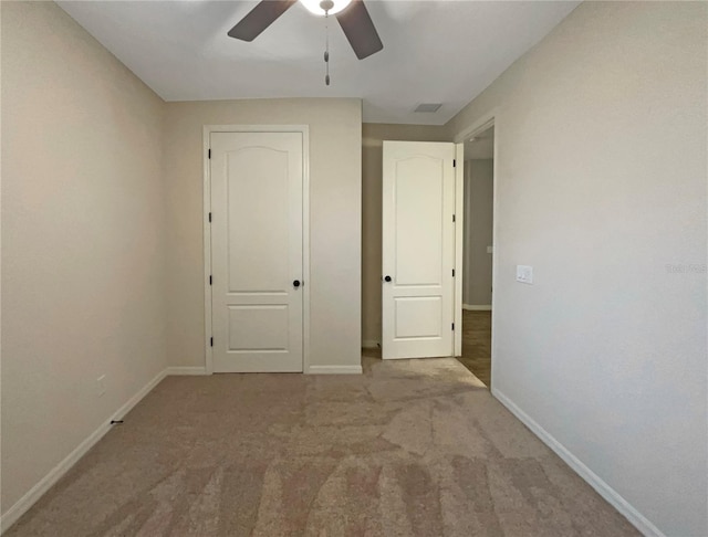 unfurnished bedroom with ceiling fan and light colored carpet