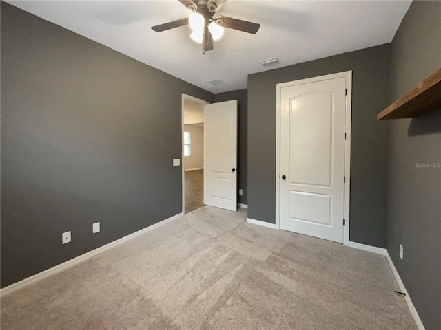 unfurnished bedroom with ceiling fan and light colored carpet