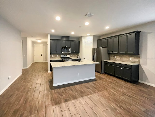 kitchen featuring a kitchen island with sink, decorative backsplash, dark hardwood / wood-style flooring, and stainless steel appliances