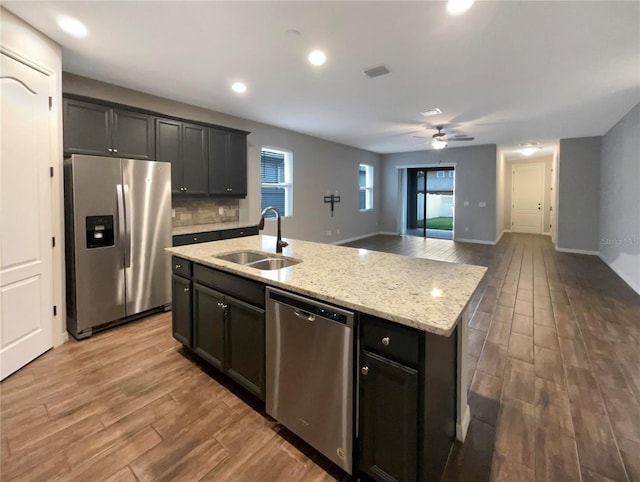 kitchen featuring a kitchen island with sink, sink, ceiling fan, appliances with stainless steel finishes, and wood-type flooring