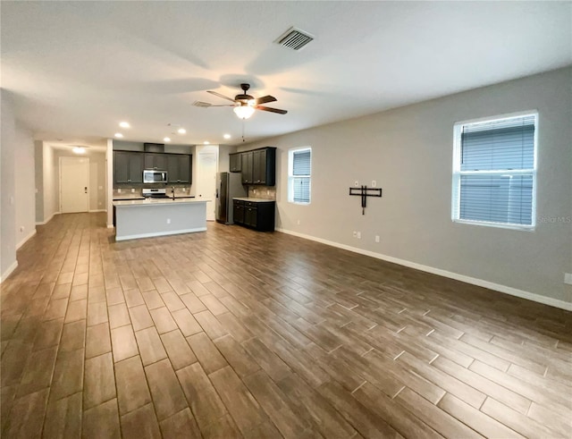 unfurnished living room with dark hardwood / wood-style flooring and ceiling fan