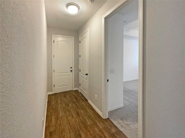 corridor with dark wood-type flooring and a textured ceiling