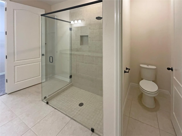 bathroom featuring tile patterned flooring, toilet, and an enclosed shower