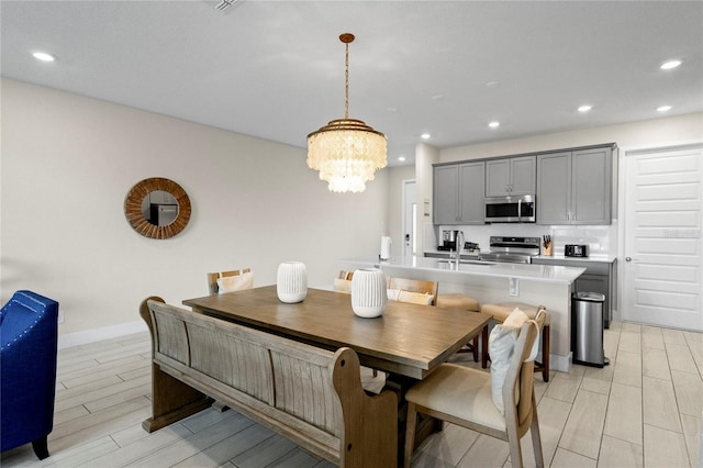 dining area featuring an inviting chandelier, light hardwood / wood-style flooring, and sink