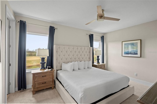 bedroom featuring ceiling fan, light colored carpet, and multiple windows