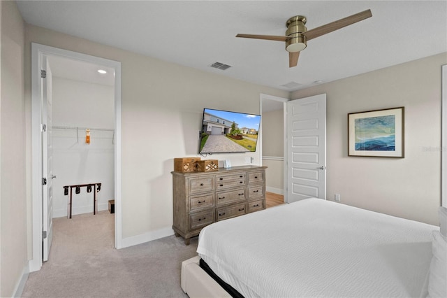 bedroom with a walk in closet, ceiling fan, and light colored carpet