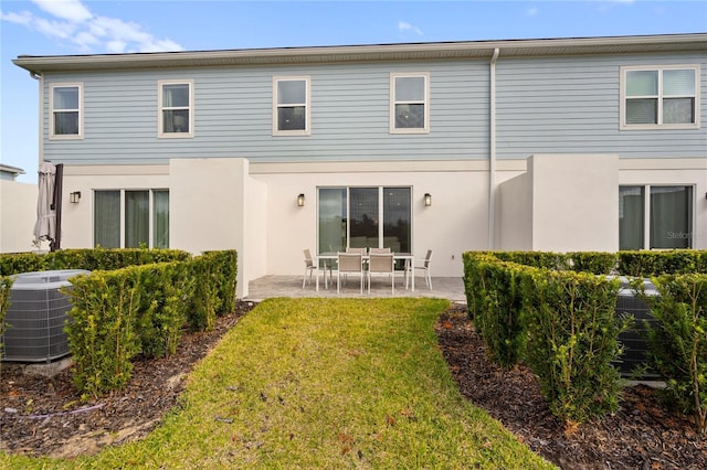 rear view of property with a lawn, a patio, and central AC unit