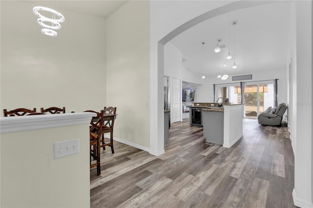 kitchen with beverage cooler, high vaulted ceiling, hardwood / wood-style floors, decorative light fixtures, and a kitchen bar